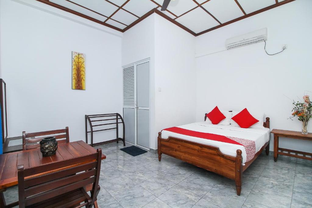 1 dormitorio con cama con almohadas rojas y escritorio en Leo's Home Stay en Colombo