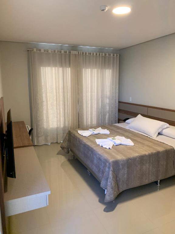 a bedroom with a large bed with towels on it at Hotel Catarina in São Miguel dʼOeste