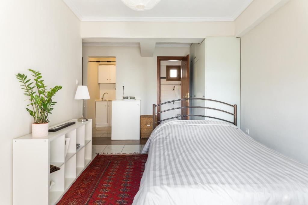 ein weißes Schlafzimmer mit einem Bett und einem roten Teppich in der Unterkunft Irodotou Studio in Thessaloniki