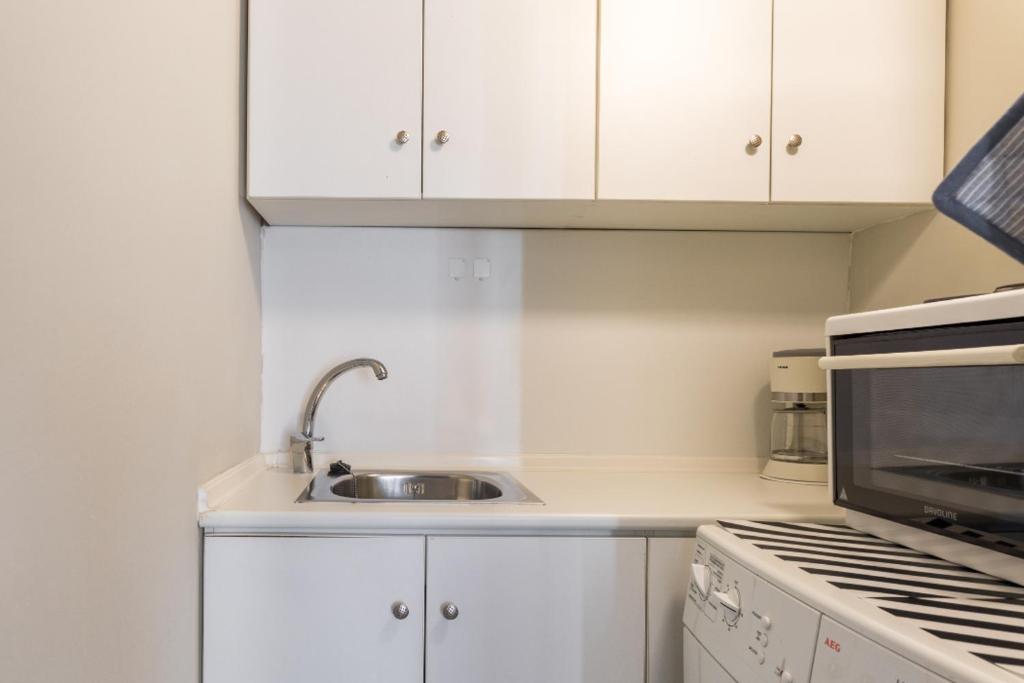 a white kitchen with a sink and a microwave at Irodotou Studio in Thessaloniki