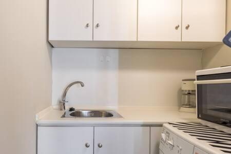 a white kitchen with a sink and a stove at Irodotou Studio in Thessaloniki