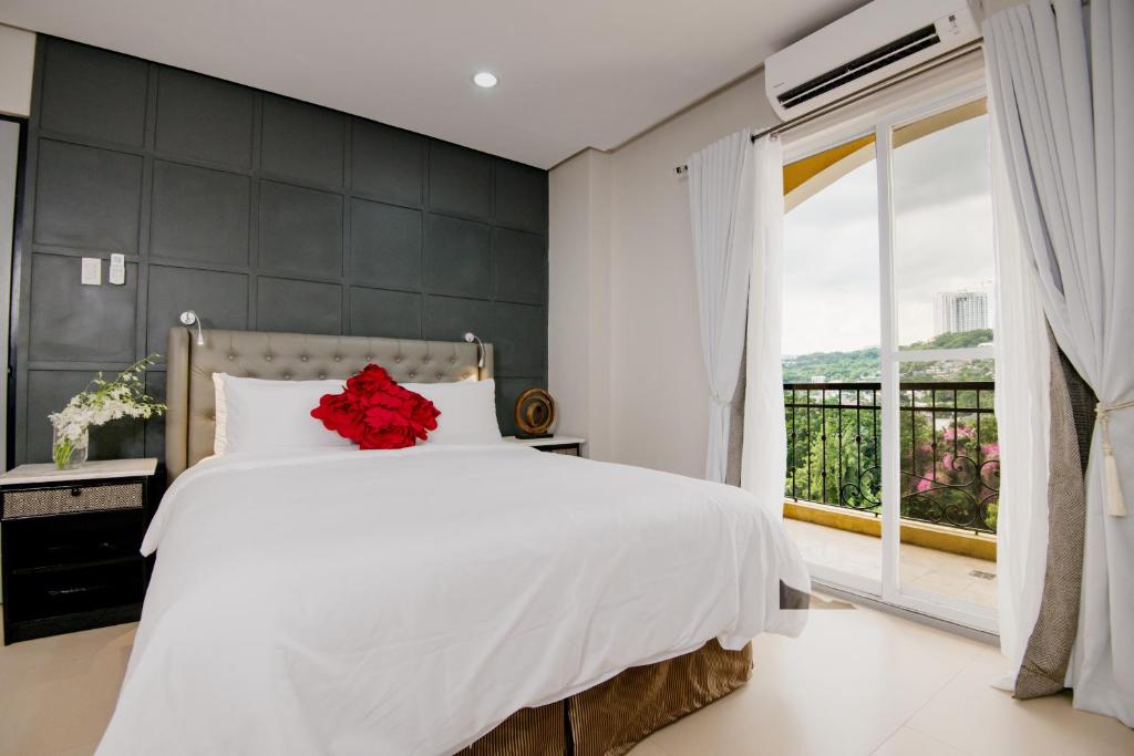 a bedroom with a white bed with a red flower on it at Sta Barbara Residence Hotel in Cebu City