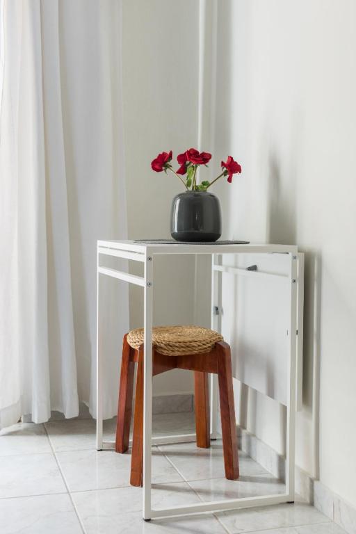 a white table with a vase with red flowers on top at Irodotou Studio in Thessaloniki