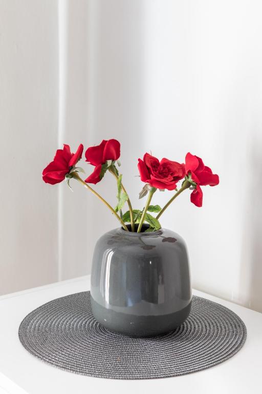 a grey vase with red flowers in it on a table at Irodotou Studio in Thessaloniki