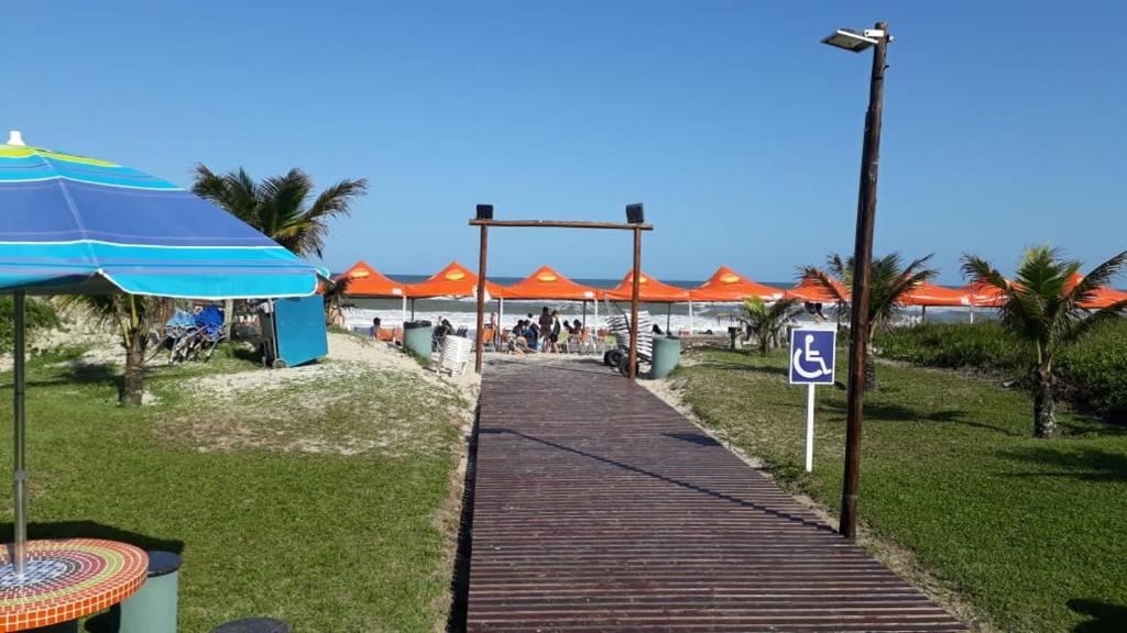una pasarela con sombrillas naranjas en la playa en Hotel Rota do Sol en Guaratuba