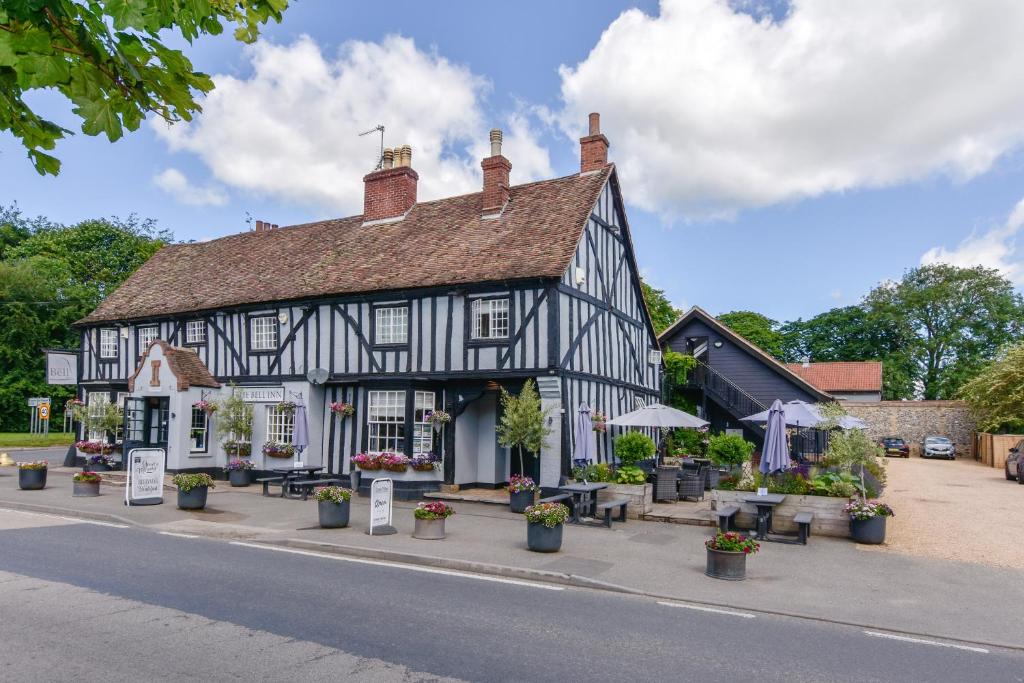 an old black and white building with flowers and plants at The Bell Inn in Newmarket