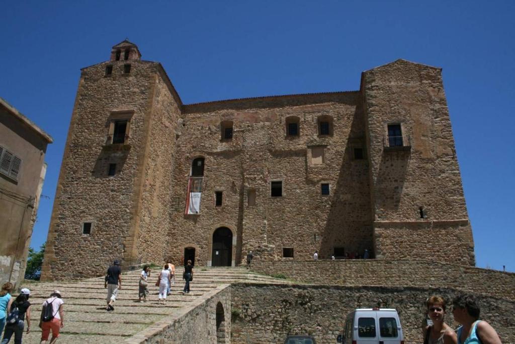 duży ceglany budynek z ludźmi idącymi po schodach w obiekcie DONJON SUITE centro storico w mieście Castelbuono