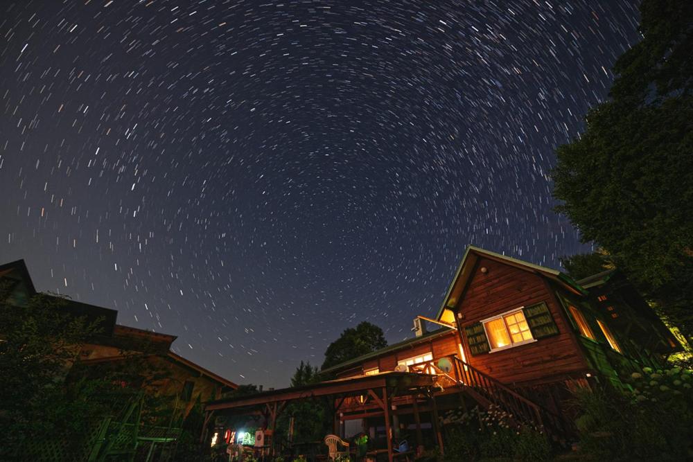 un cielo estrellado sobre una cabaña por la noche en ペンション イメージハウス, en Hara
