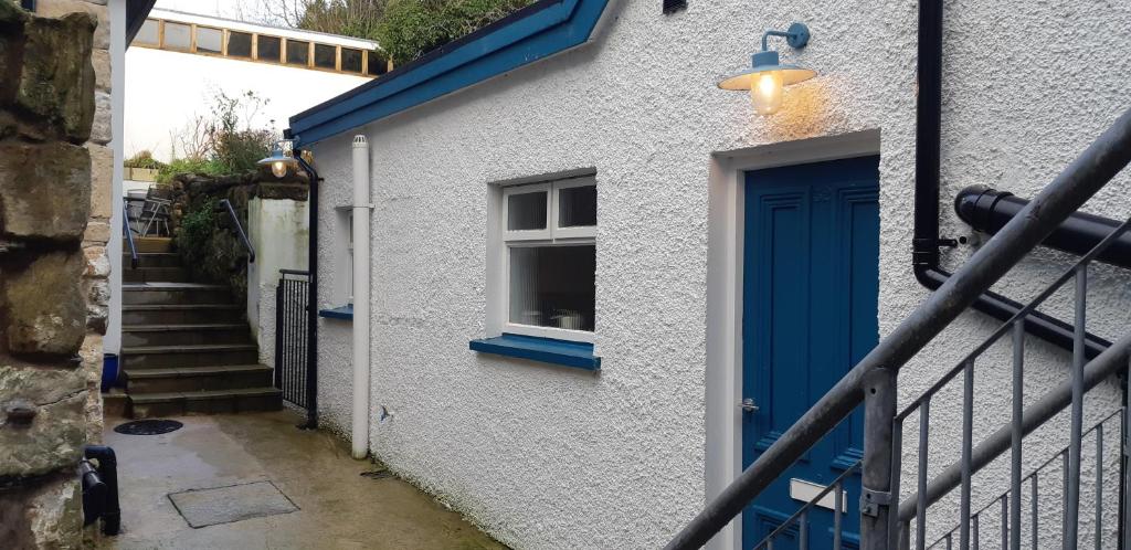 a blue door on a white building with a window at Ballycastle Town Centre Apartment in Ballycastle