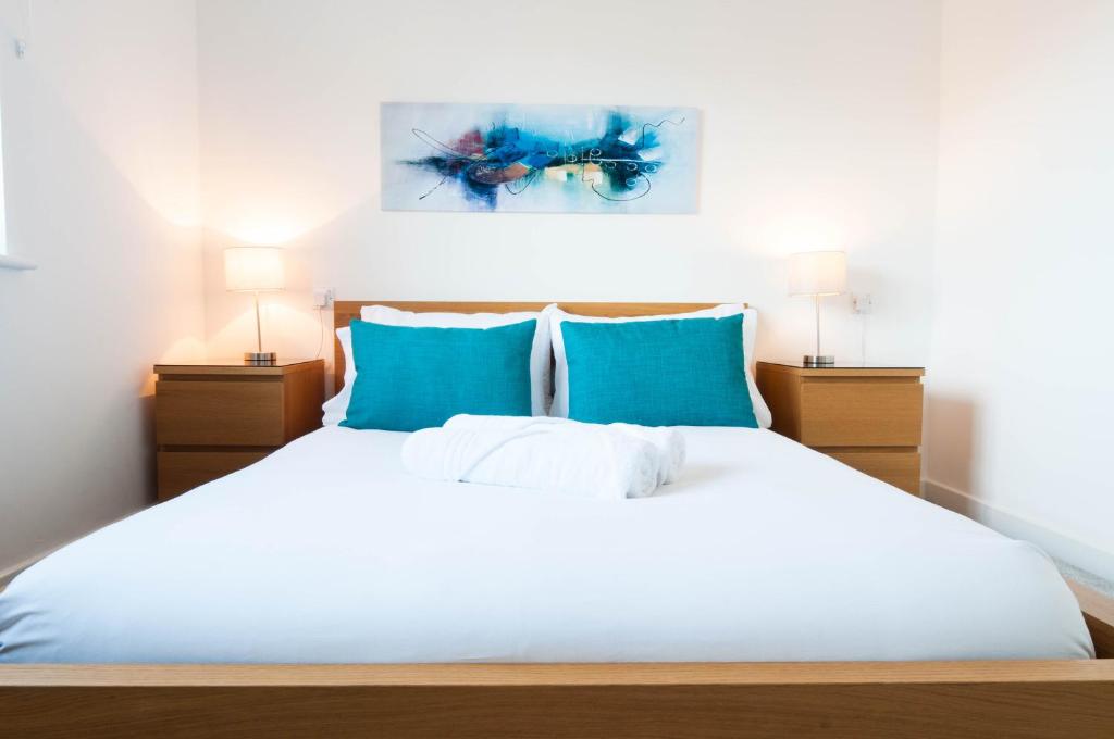 - une chambre avec un lit blanc et des oreillers bleus dans l'établissement The Dakota - next to East Midlands Airport, à Castle Donington