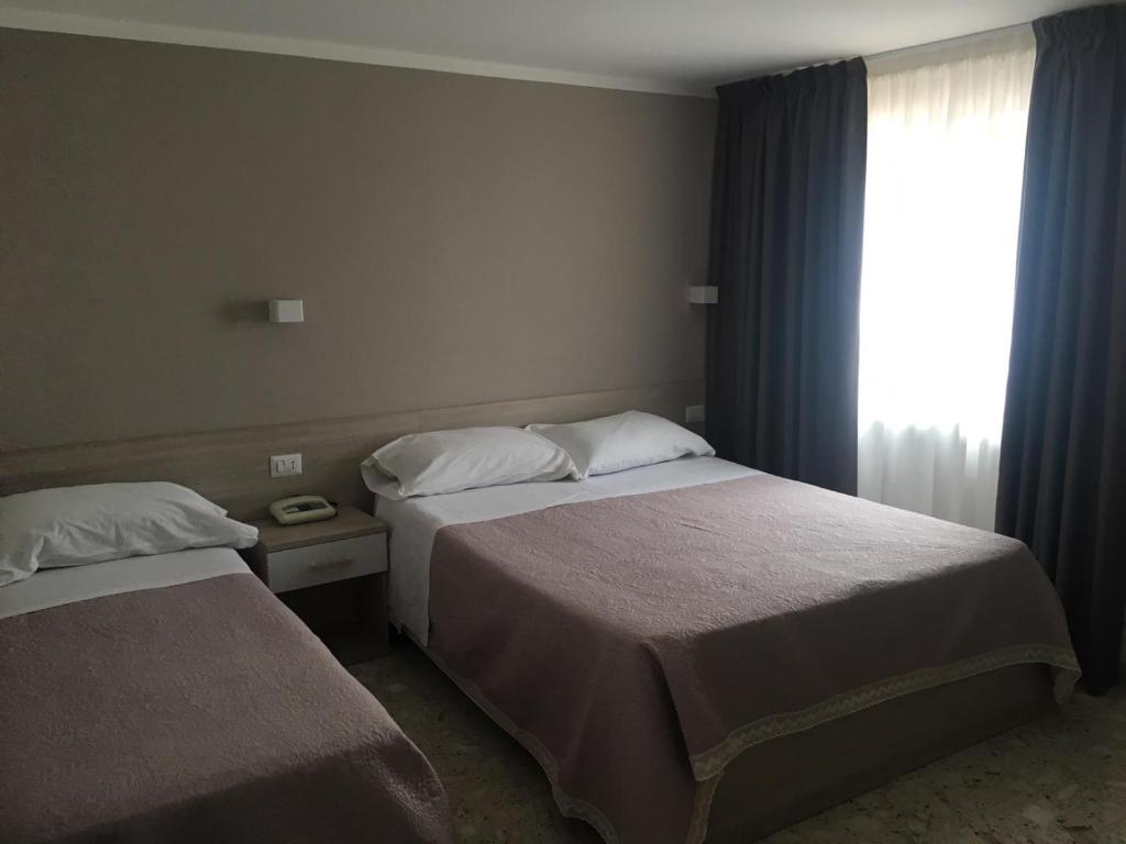 聖圖費米亞拉梅齊亞的住宿－Piccolo Hotel Lamezia，酒店客房设有两张床和窗户。