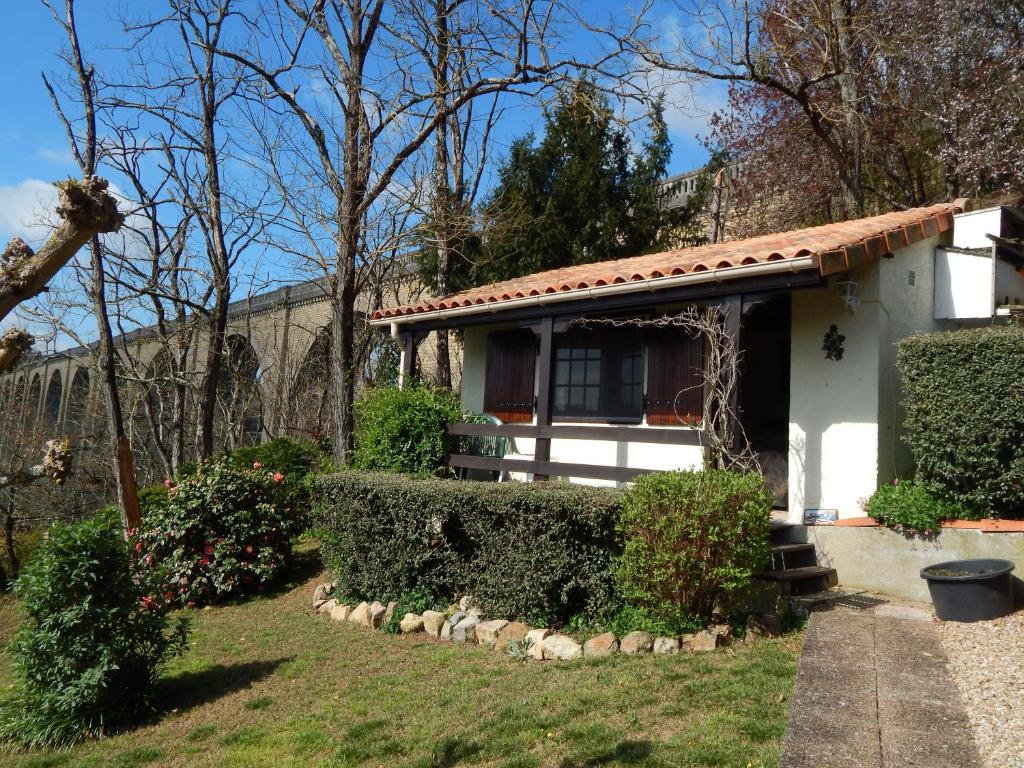 a small white house with bushes and trees at The Petite Chalet Chambre d'hôtes in LʼIsle-Jourdain