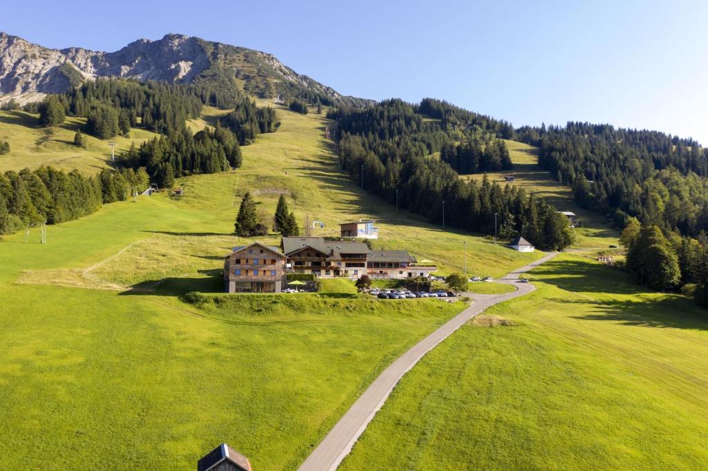 una casa su una collina erbosa con una strada di Biohotel Mattlihüs a Bad Hindelang