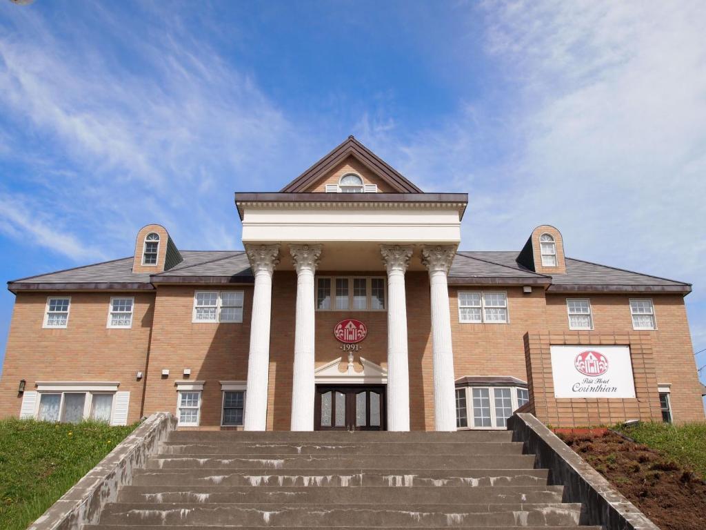 un grande edificio in mattoni con colonne e scale bianche di Petit Hotel Corinthian a Rebun