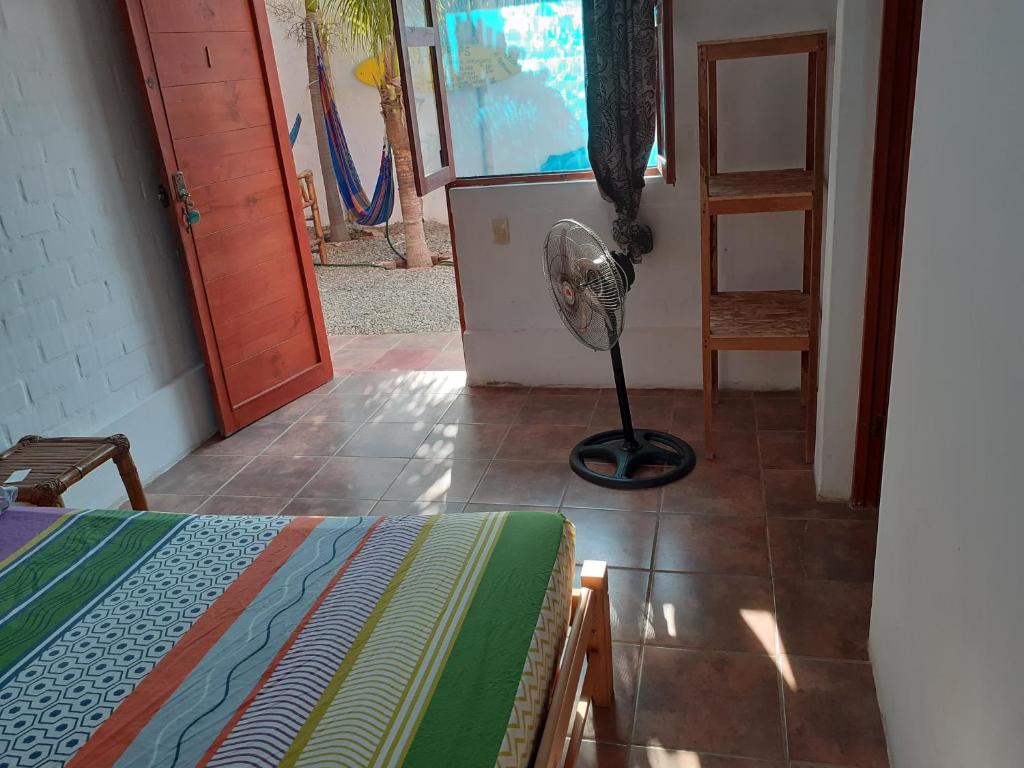 a room with a bed and a fan on the floor at Casa Máncora Guesthouse in Máncora