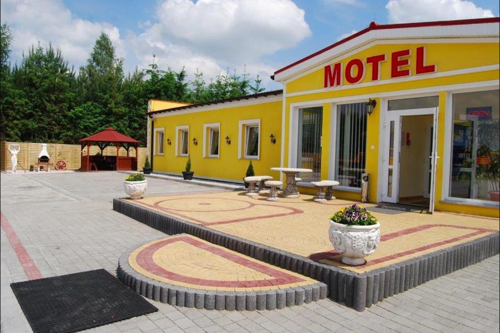 a yellow motel with a table in front of it at Motel Kochlice in Kochlice