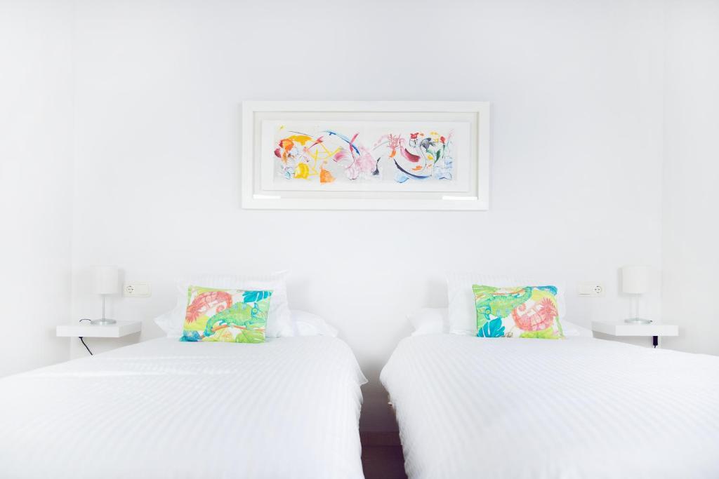 2 camas en una habitación blanca con una foto en la pared en Hispalis Casa Palacio Apartment en Sevilla