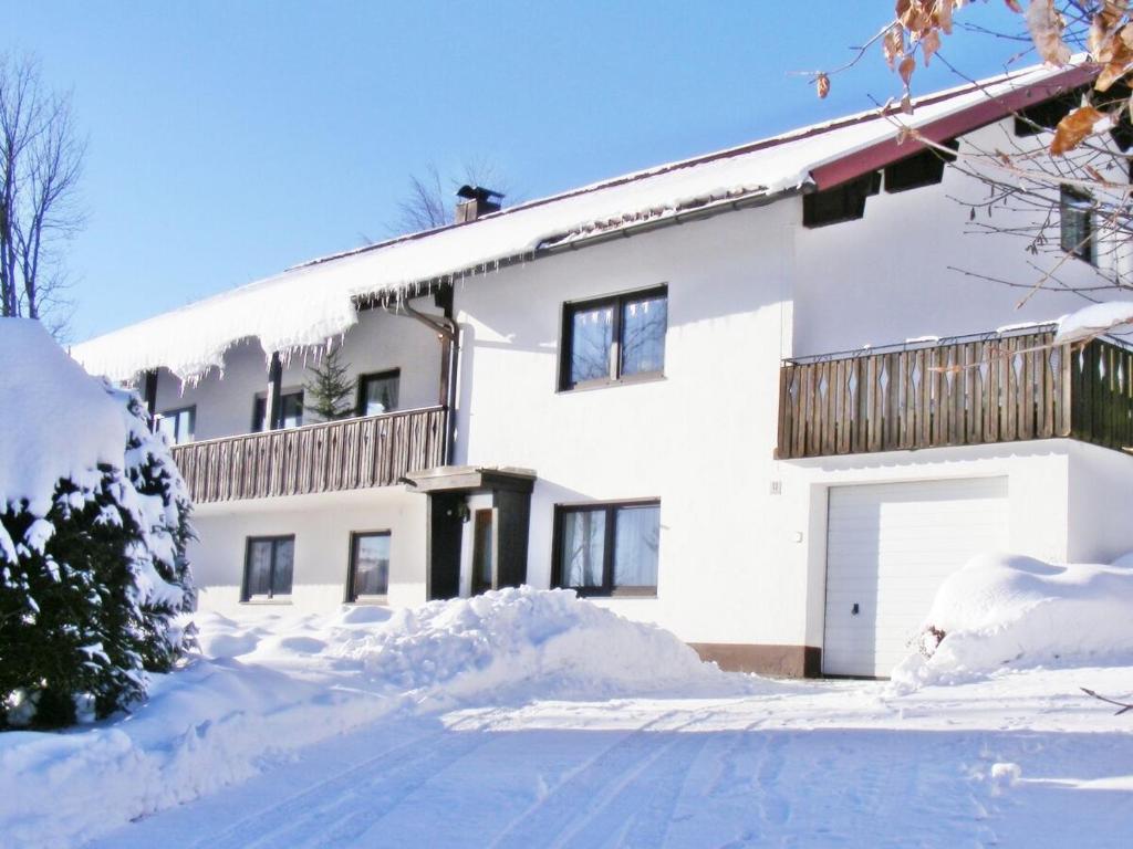uma casa branca com muita neve à frente. em Ferienwohnung- Pfenniggeiger em Philippsreut