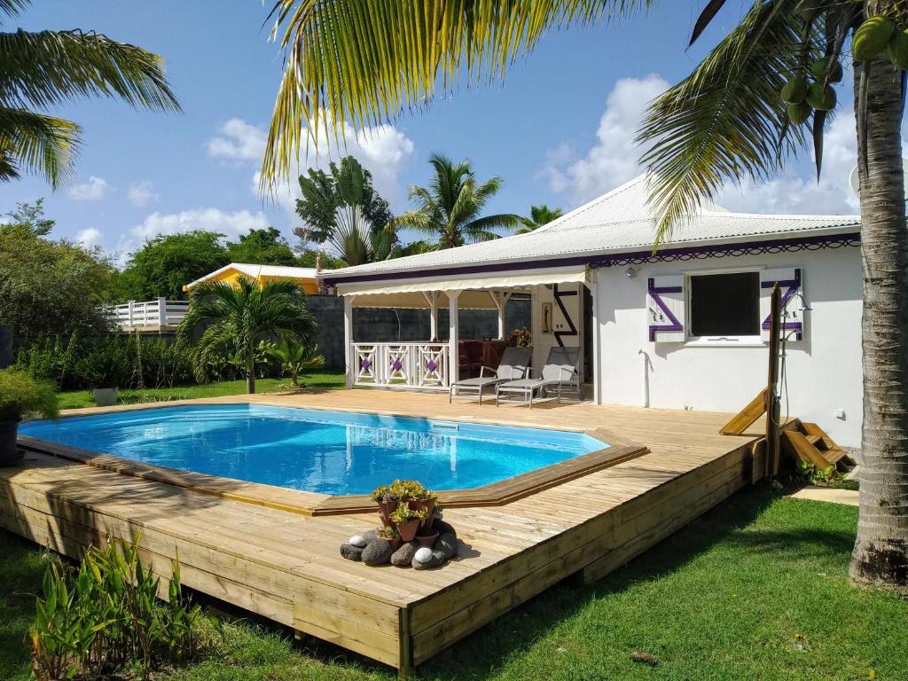 a swimming pool with a wooden deck and a house at Villa & Bungalow Fleur de Coco in Sainte-Anne