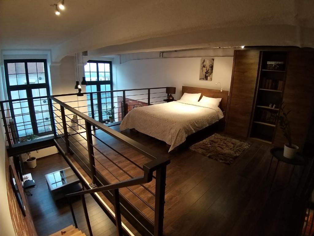 a bedroom with a bed and a staircase with windows at LOFT 314 in Żyrardów