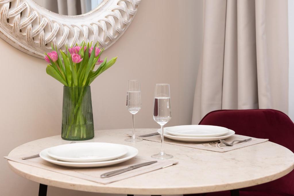 einen Tisch mit Tellern und Gläsern und eine Vase mit Blumen in der Unterkunft Hotel Meltzer Apartments in Tallinn