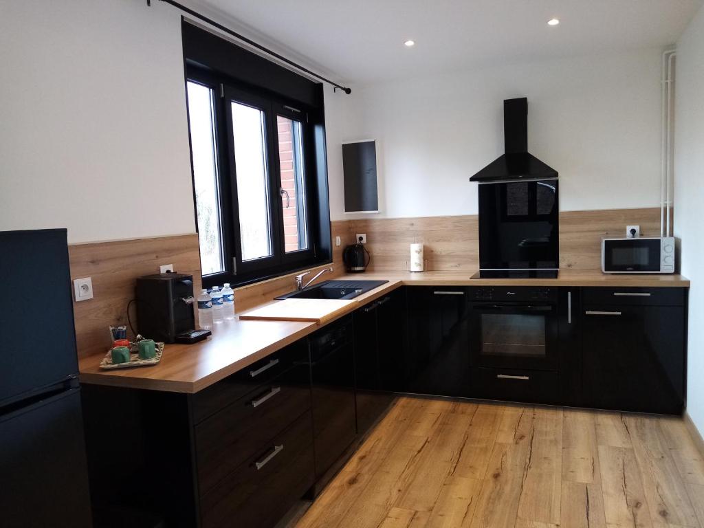 a kitchen with black cabinets and a sink and a window at Duplex agréable et spacieux 3 chb dont 1 communicante in Vendeville