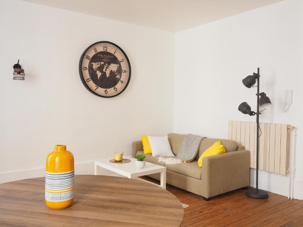 uma sala de estar com um sofá e um relógio na parede em Appartement le st jean - centre historique em Valence