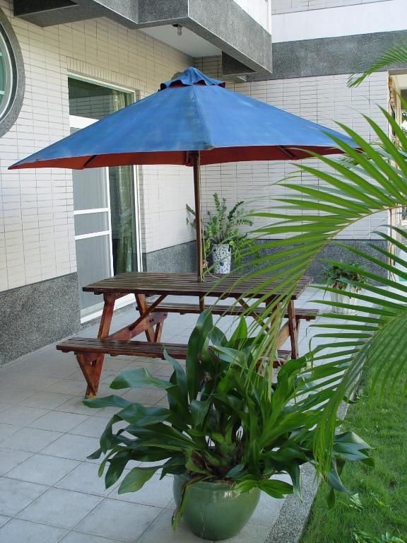 a picnic table with a blue umbrella on a patio at Feng Lin Homestay in Shuili