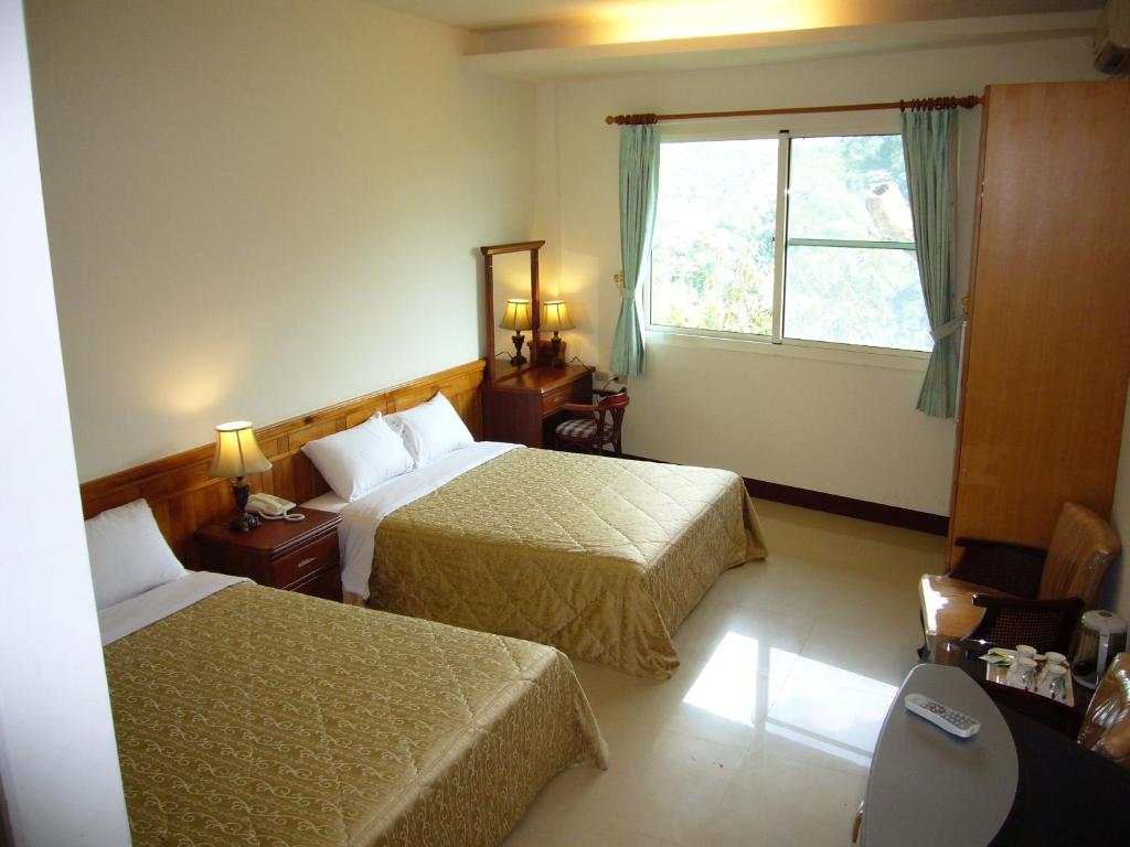 a hotel room with two beds and a window at Feng Lin Homestay in Shuili