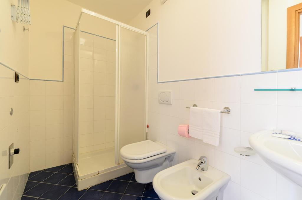 a white bathroom with a toilet and a sink at Le Tartarughe Aparthotel in Letojanni