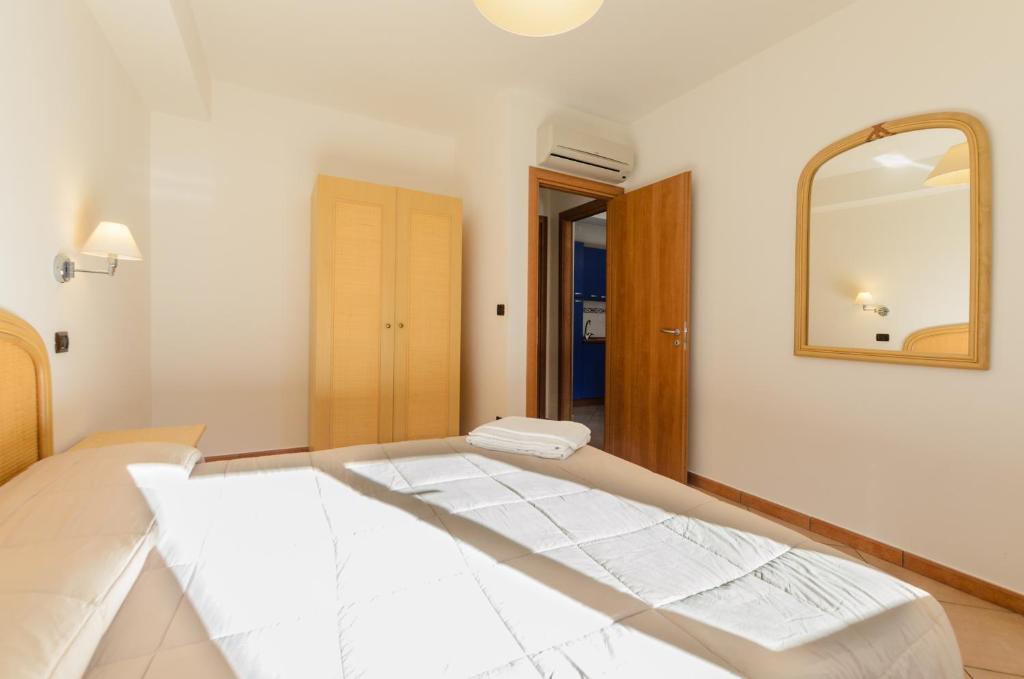 a white room with a mirror and a bed at Le Tartarughe Aparthotel in Letojanni