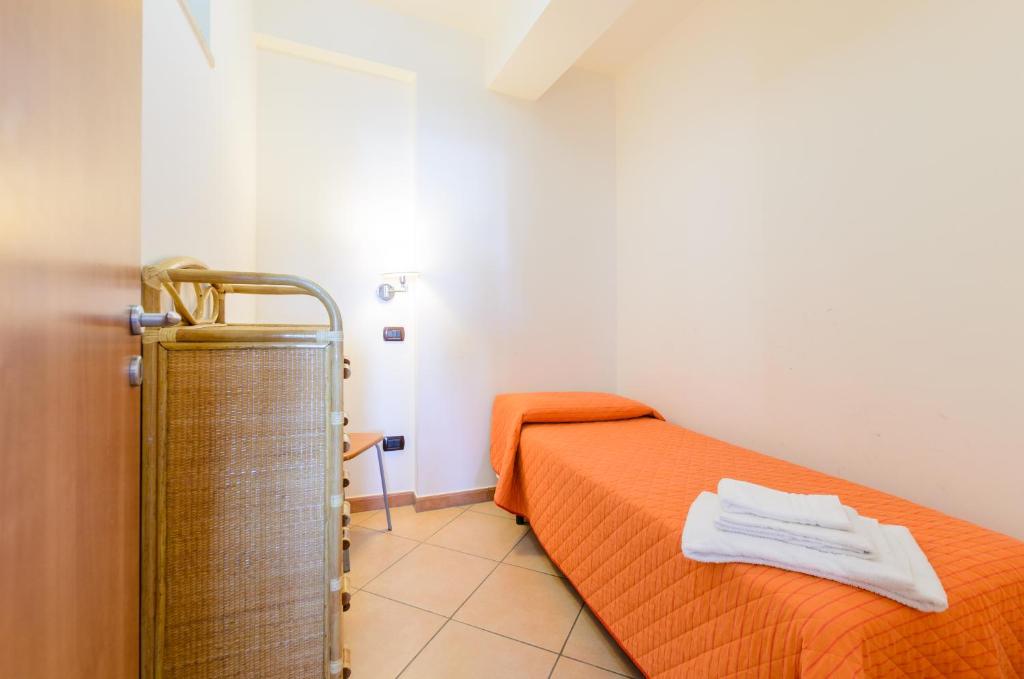 a room with two beds with orange sheets and a towel at Le Tartarughe Aparthotel in Letojanni