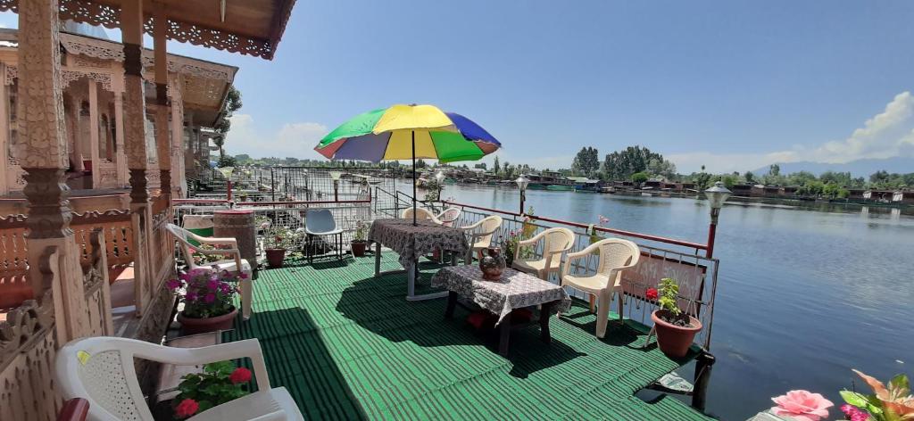 eine Terrasse mit Tischen, Stühlen und einem Sonnenschirm in der Unterkunft Lake Palace Group Of House Boats in Srinagar