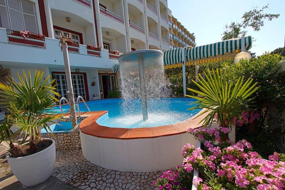 a fountain in the middle of a courtyard with a building at Golf & Beach Hotel B&B in Milano Marittima