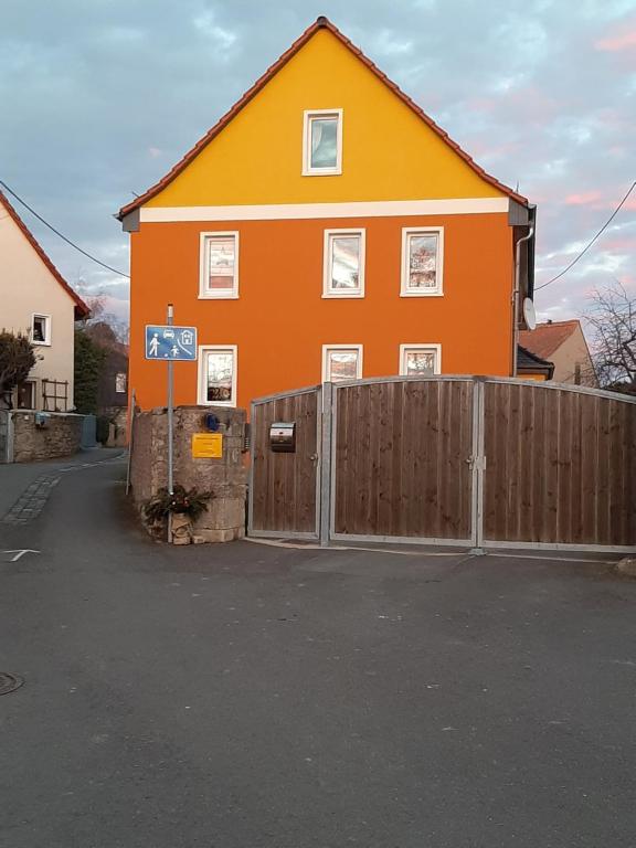 una casa naranja con una valla y una puerta en Ferienwohnung Familie Seel, en Weimar