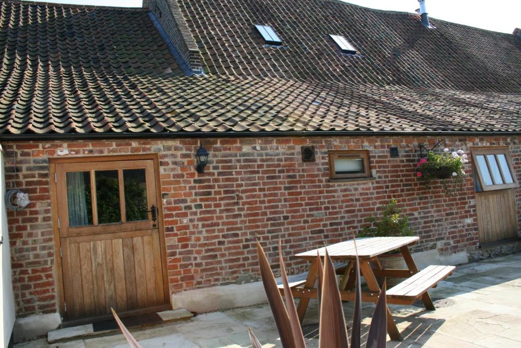 a brick building with a wooden door and a table at Camps Heath Barn in Lowestoft