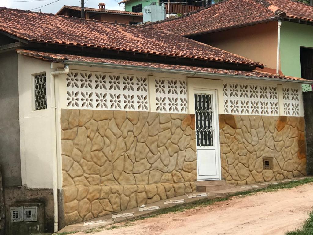 une maison avec un mur en pierre et une porte blanche dans l'établissement Casa do campo, à Ibitipoca