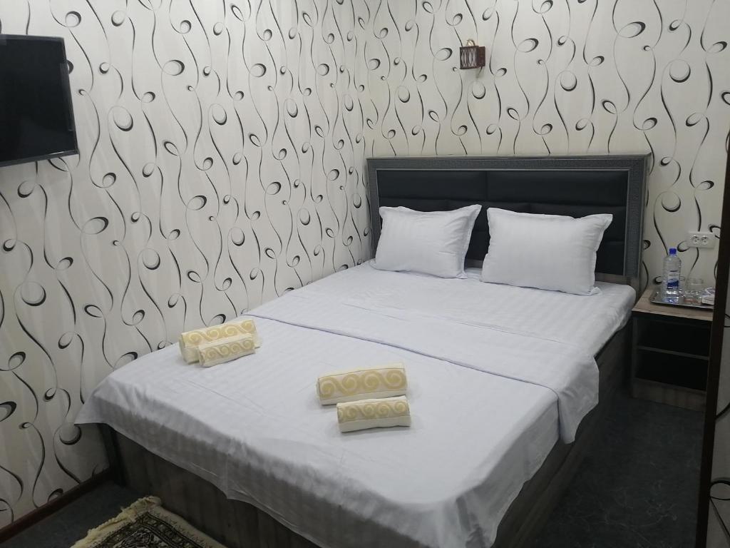 1 dormitorio con 1 cama con 2 toallas en Aziz Hotel, en Samarkand