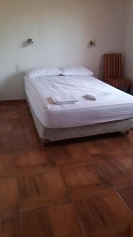 Cama blanca en habitación con suelo de madera en Cabaña 508km en San Rafael