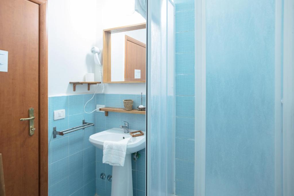 niebieska łazienka z umywalką i lustrem w obiekcie Gialel Guesthouse w Rzymie