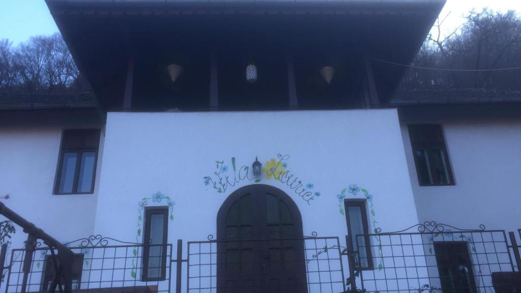 - un bâtiment blanc avec une porte et un panneau dans l'établissement Vila Licurici, à Căciulata