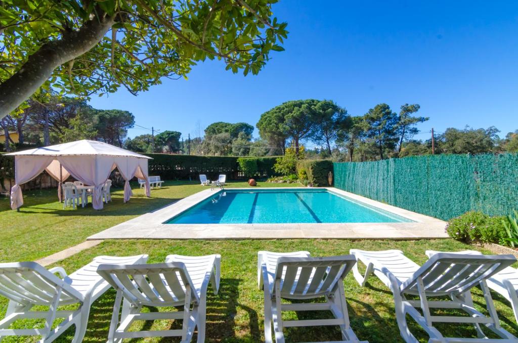 uma piscina com espreguiçadeiras brancas e uma cerca em Club Villamar - Aygo em Maçanet de la Selva