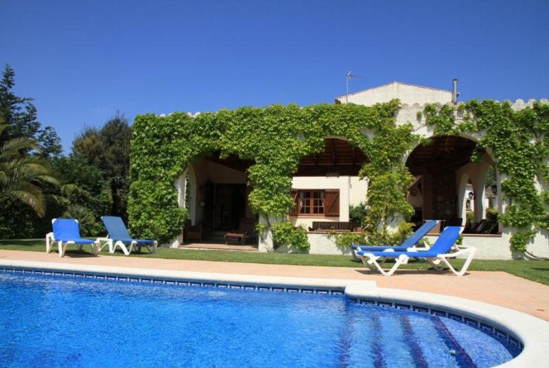 a house with two blue chairs and a swimming pool at Club Villamar - Quietud in Santa Cristina d'Aro