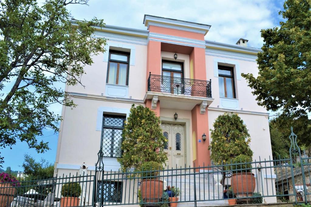 a pink and white house with a black fence at Vogiatzopoulou Guesthouse in Agios Georgios Nilias