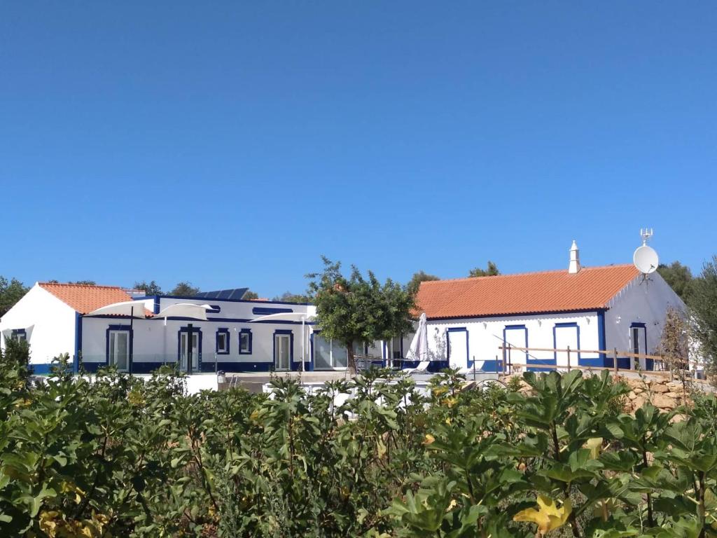 een wit gebouw met een rood dak in een veld bij Monte das Perdizes in Olhão