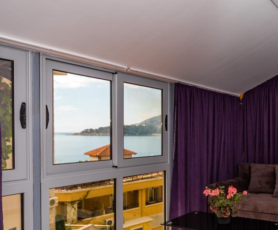 ein Wohnzimmer mit Fenstern und Blick auf das Wasser in der Unterkunft Blue sea apartments by ArniCare in Rafailovici