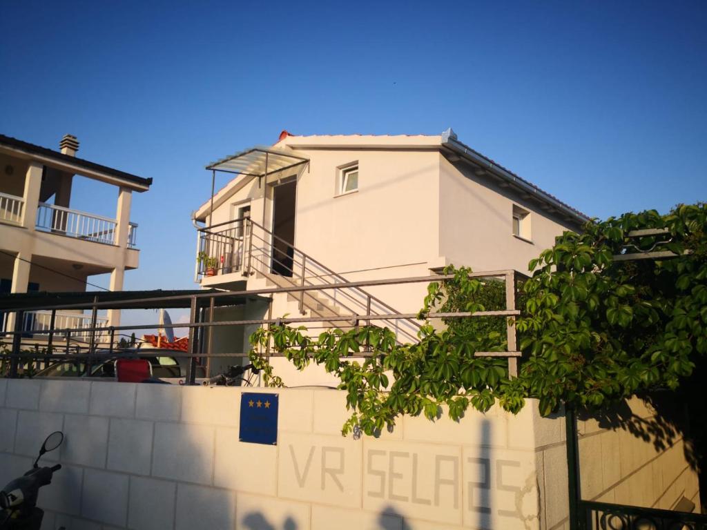 a white building with a balcony on top of a wall at Apartman Barada in Slatine
