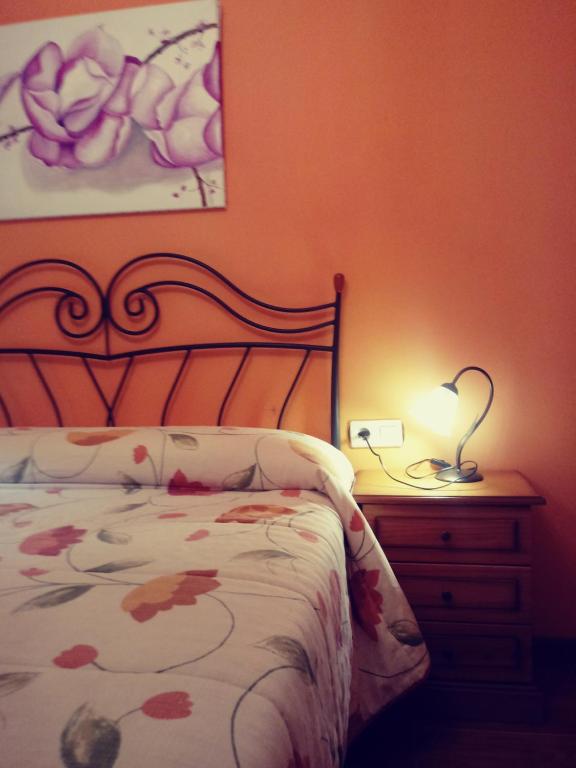 Casa rural el cerrete في ريوبار: غرفة نوم مع سرير ومصباح على كومودينو