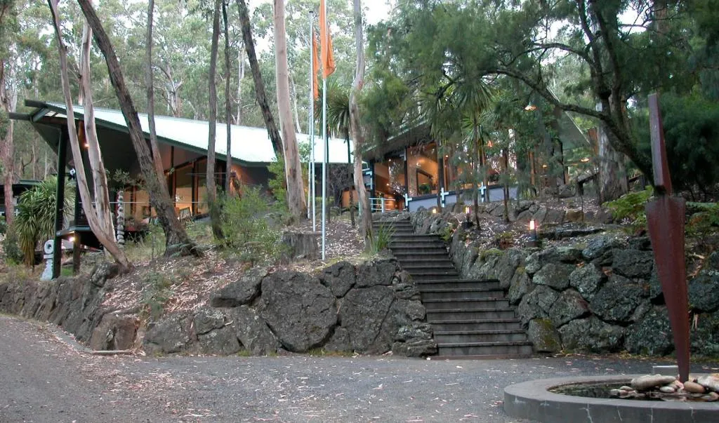 Stone steps up to a low building among gum trees and a sculpture