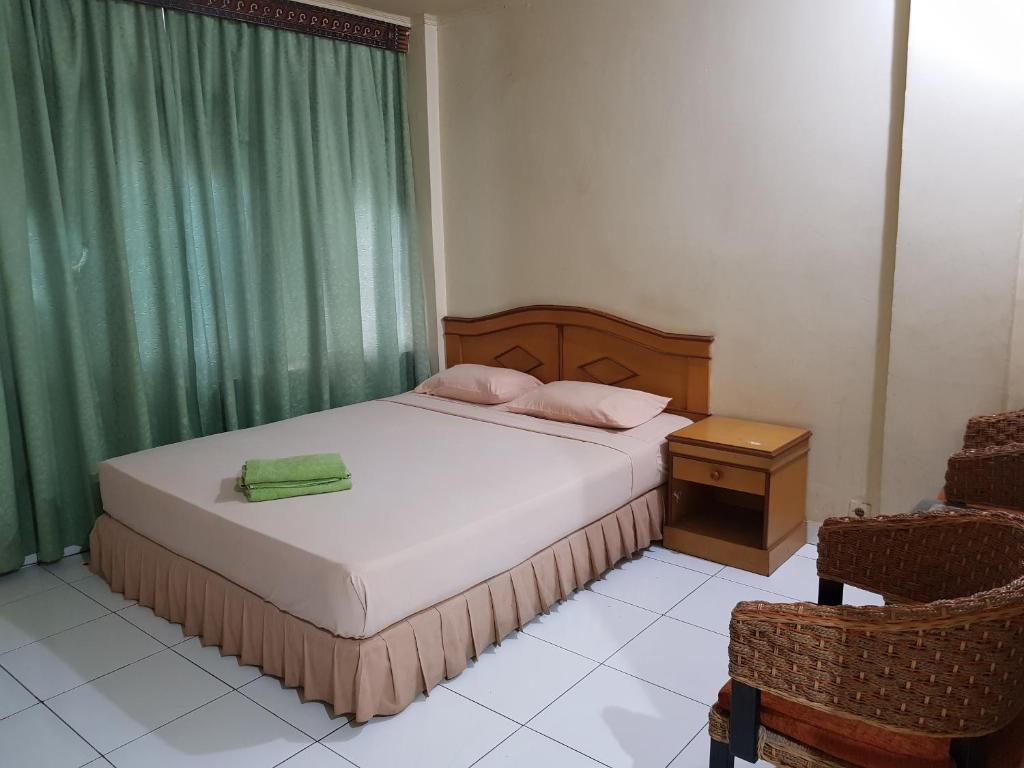 a small bedroom with a bed and a chair at OYO 2941 Hotel Istana in Makassar
